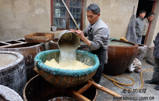 滤洗前,陆方标往大筲箕里倒水.